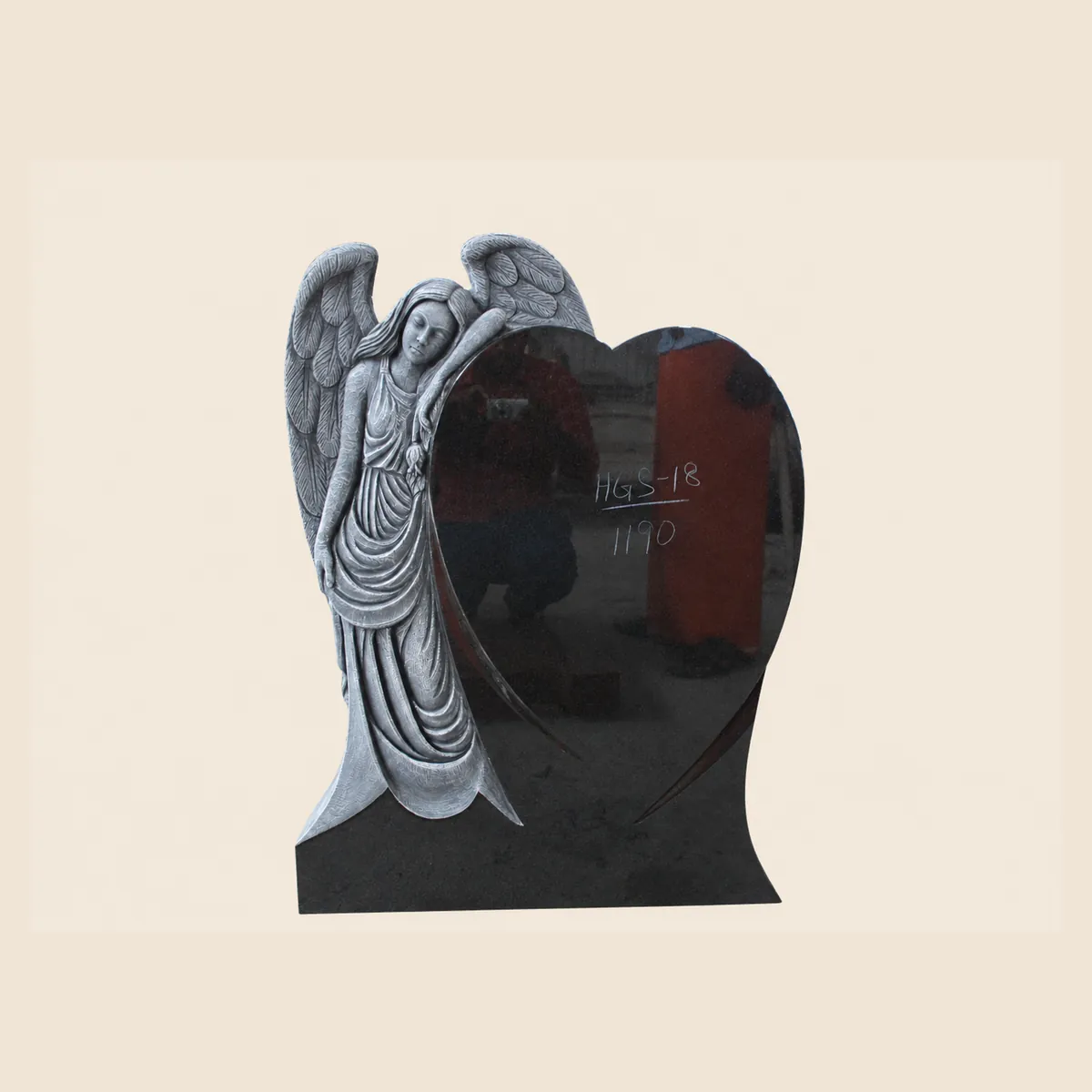 Standing angel carved beside a polished black granite heart