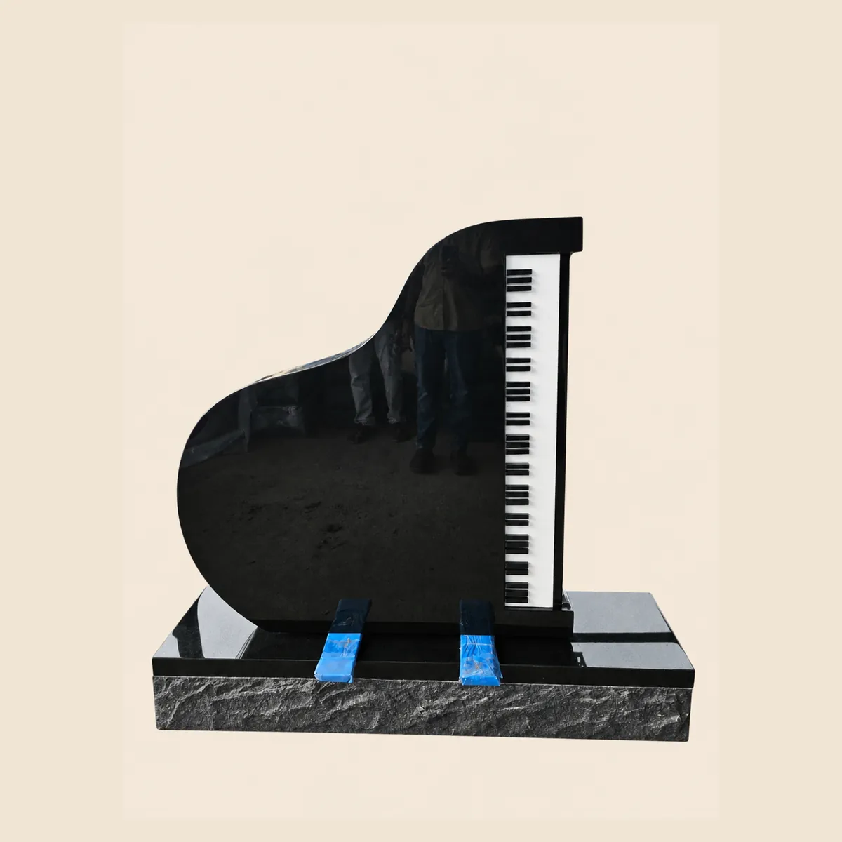 Black granite grand-piano memorial with a polished keyboard on a rock-pitched base