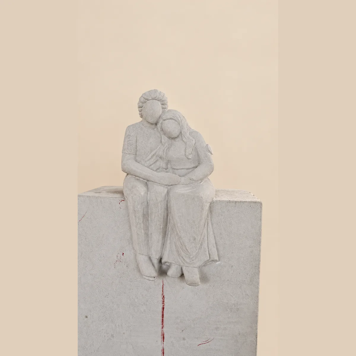 Parents and child seated together, carved in cream granite
